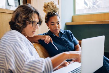 Two individuals reviewing employer-sponsored healthcare coverage details together on a laptop